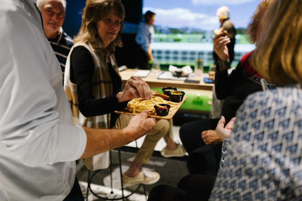 Guests sharing food at an event at X-Golf Pittsford