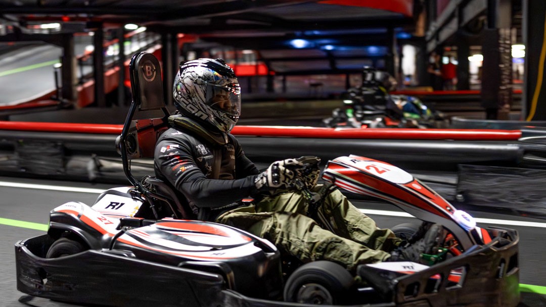 Driver racing a go-kart on an indoor track